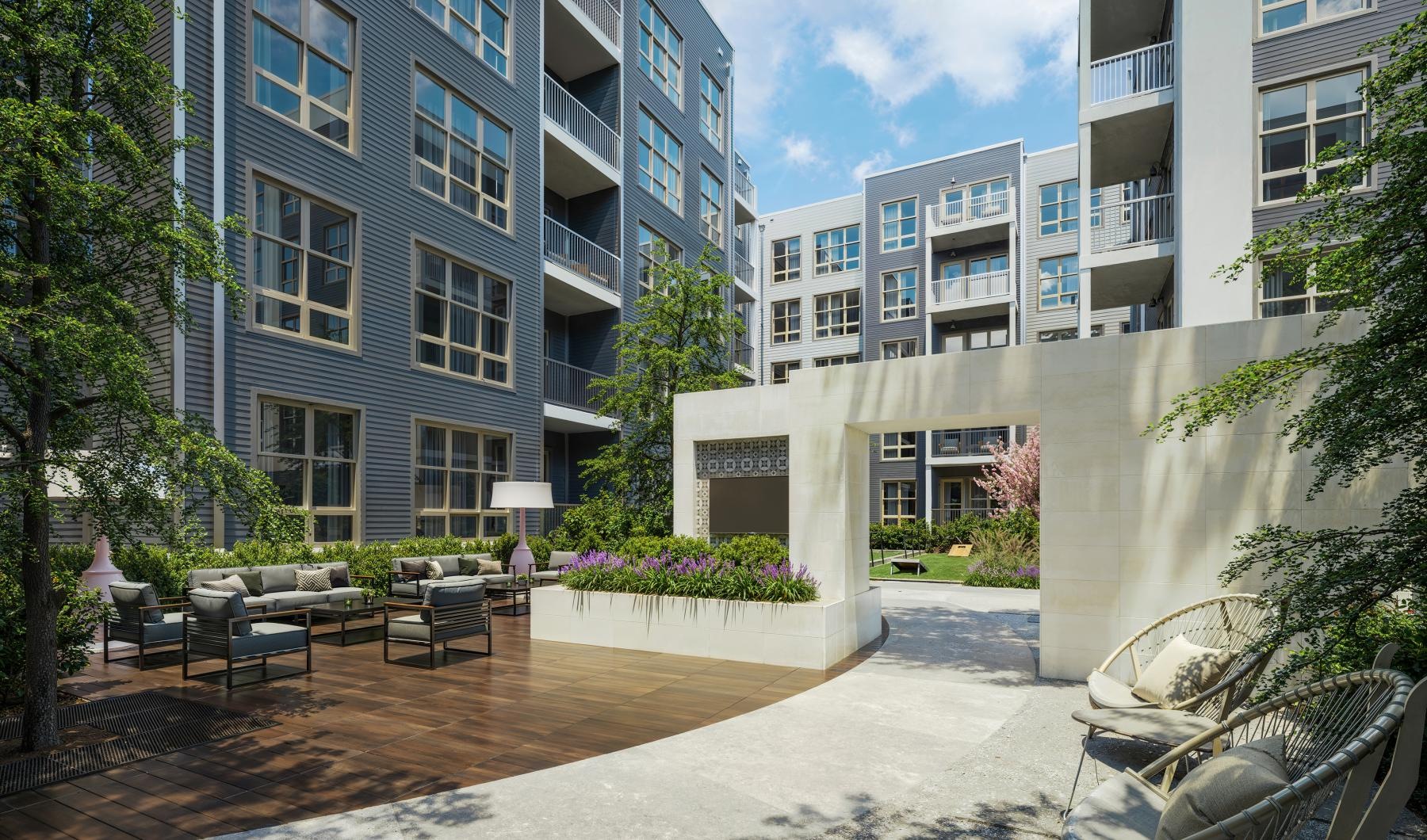 a courtyard with chairs and tables and trees in front of a building