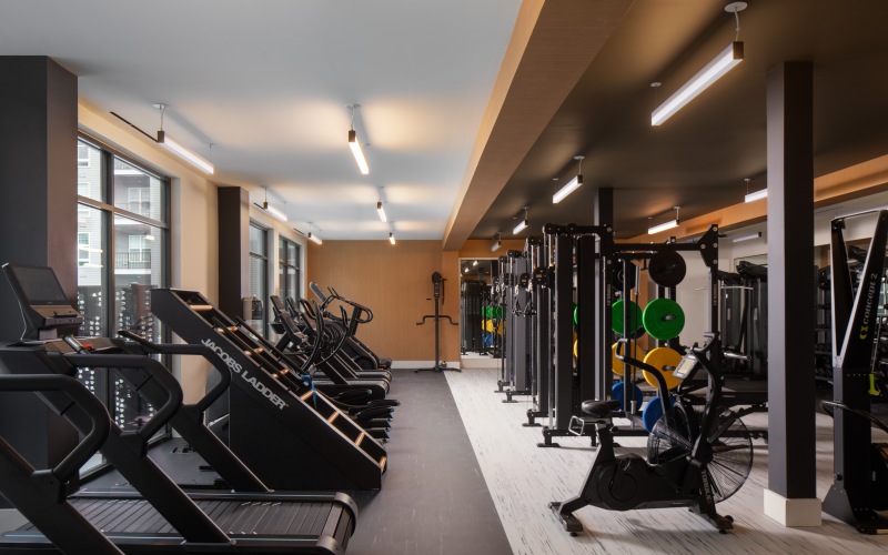a gym with various exercise equipments including weights treadmills and a stair stepper 
