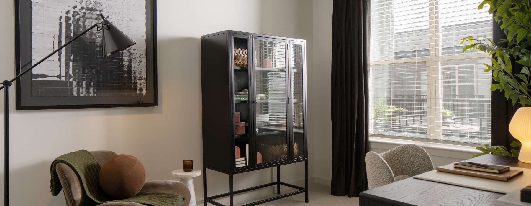 a room with a large window with desk a few chairs and a bookcase 