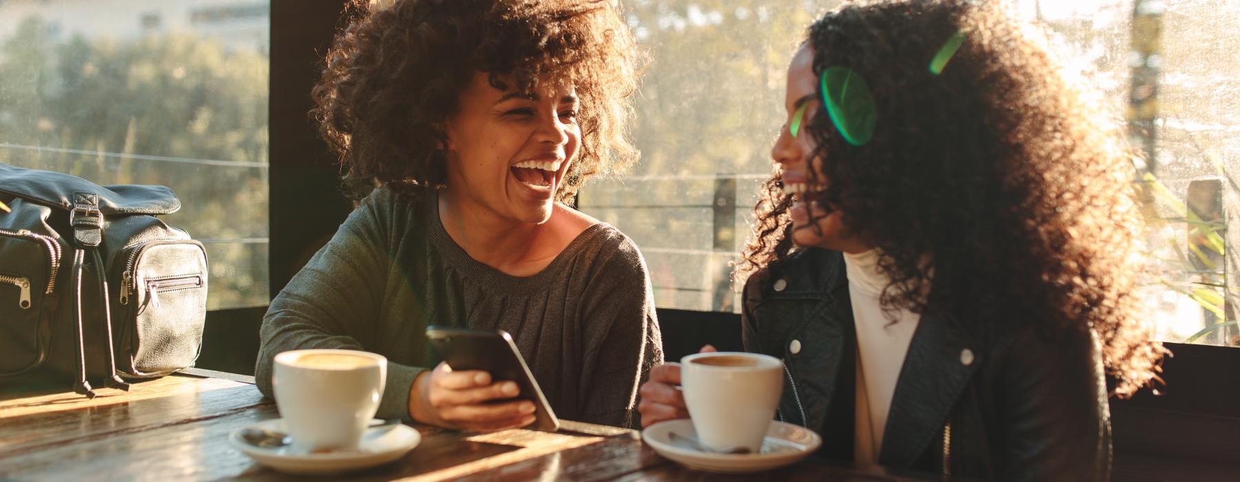 a couple of women sitting at a table with coffee and a tea cup