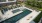 a swimming pool with chairs next to a building