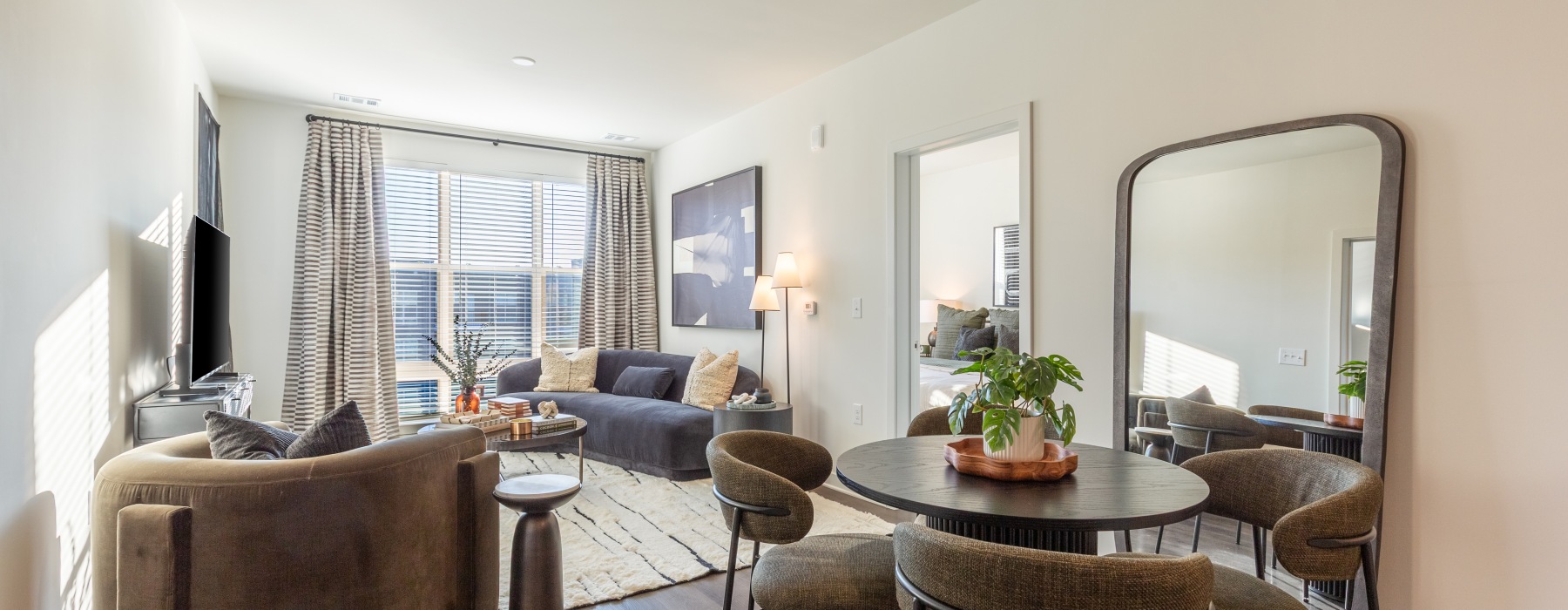 well lit living room with couch and rug and a dining table with chairs